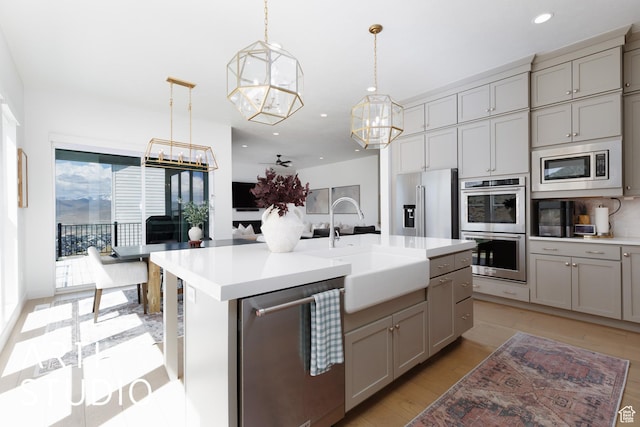 kitchen featuring appliances with stainless steel finishes, gray cabinets, a chandelier, a sink, and recessed lighting