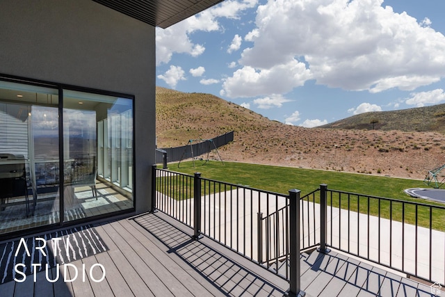 wooden deck with a mountain view and a lawn