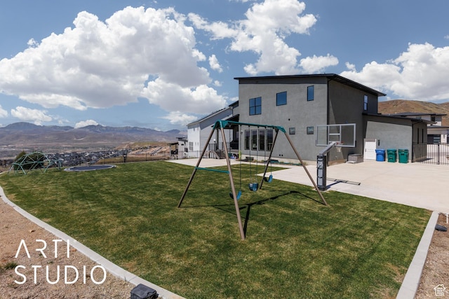 back of house with a playground, stucco siding, a mountain view, and a patio