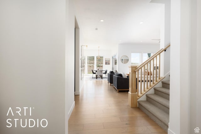 hall with light wood-type flooring, stairs, recessed lighting, and baseboards