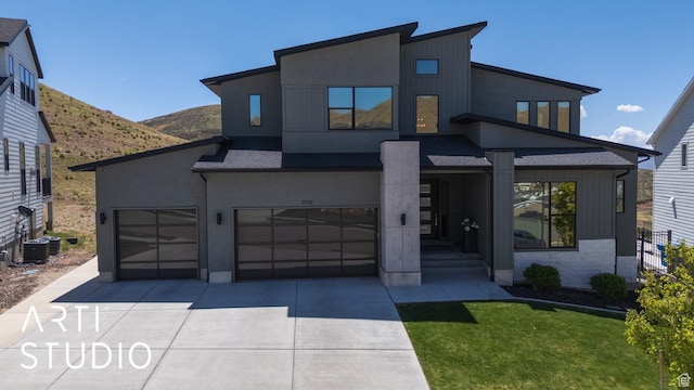 modern home featuring driveway, a mountain view, stucco siding, and an attached garage