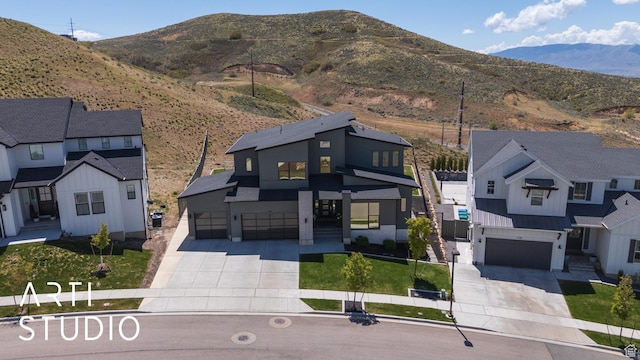 view of front facade featuring concrete driveway, an attached garage, and a mountain view