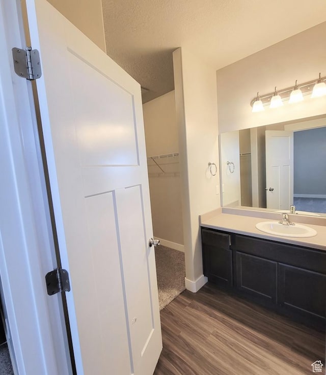 14643 S Mckellen Dr W Unit D302, Herriman, UT 84096 - bathroom featuring wood finished floors, vanity, baseboards, a spacious closet, and a textured ceiling
