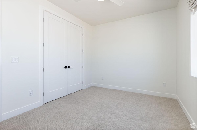 unfurnished bedroom featuring light colored carpet, baseboards, and a closet