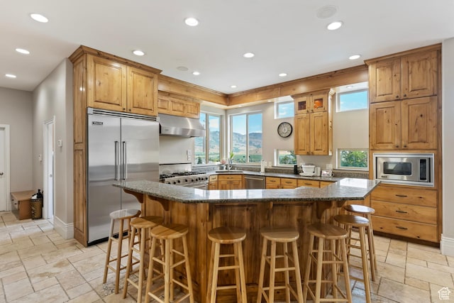 2333 S Falcon Way, Huntsville, UT 84317 - kitchen featuring built in appliances, under cabinet range hood, stone tile floors, recessed lighting, and a breakfast bar area