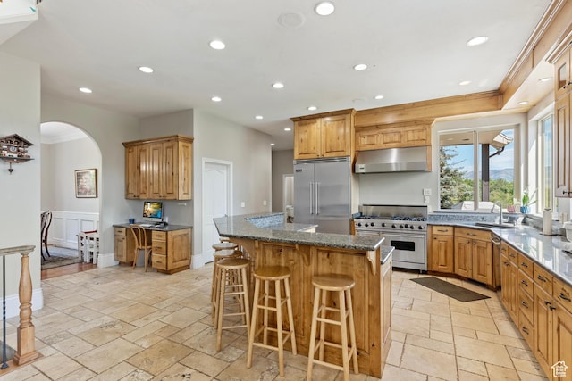 2333 S Falcon Way, Huntsville, UT 84317 - kitchen featuring high end appliances, under cabinet range hood, arched walkways, stone tile floors, and a kitchen island