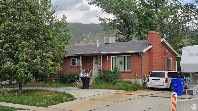 707 S Main, Centerville, UT 84014 - view of front facade featuring brick siding, a chimney, a mountain view, driveway, and central AC