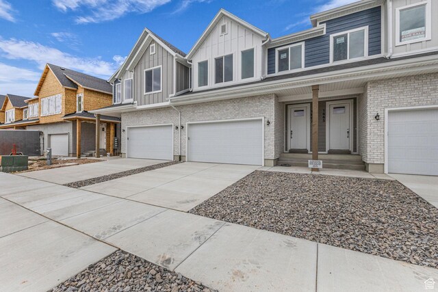 1667 W 2770 S Unit 206, Syracuse, UT 84075 - townhome / multi-family property with board and batten siding, an attached garage, driveway, brick siding, and a residential view