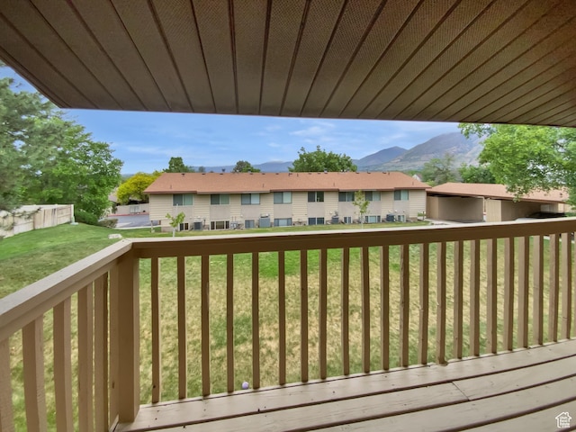 deck with a residential view, a mountain view, and a yard