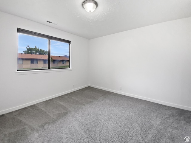 empty room with dark carpet and baseboards