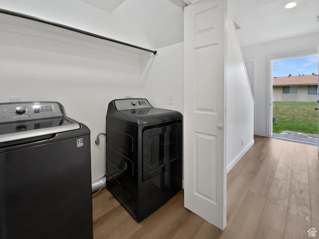 clothes washing area featuring washing machine and dryer and light wood-style floors