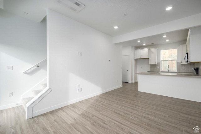 317 W Azure Sky Ln Unit 5-23, Salt Lake City, UT 84103 - kitchen with light wood finished floors, stainless steel microwave, recessed lighting, white cabinetry, and a peninsula