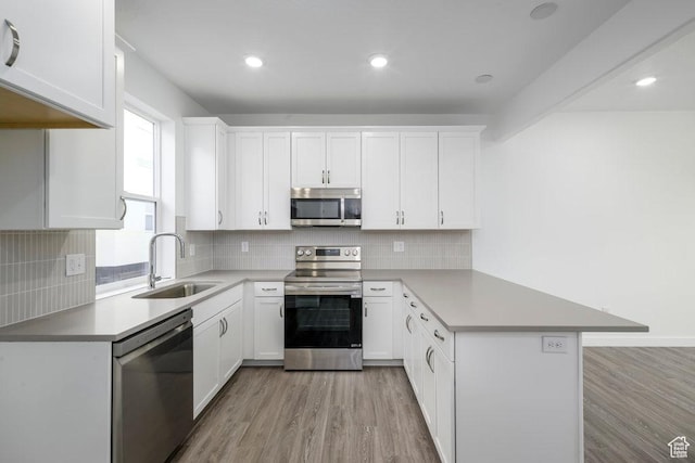 317 W Azure Sky Ln Unit 5-23, Salt Lake City, UT 84103 - kitchen featuring stainless steel appliances, a sink, a peninsula, light wood-style floors, and white cabinets