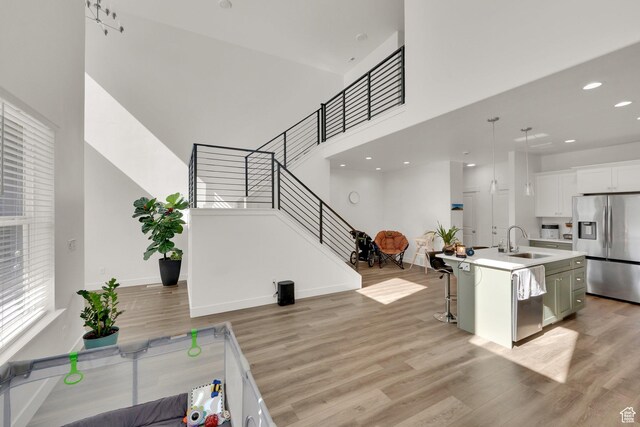 1293 N 3960 W Unit 457, Lehi, UT 84043 - kitchen with appliances with stainless steel finishes, a sink, light wood finished floors, a kitchen breakfast bar, and light countertops