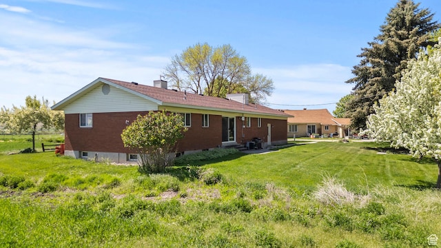 3647 Maple Creek Rd N, Franklin, ID 83237 - back of property featuring entry steps, a chimney, brick siding, and a lawn