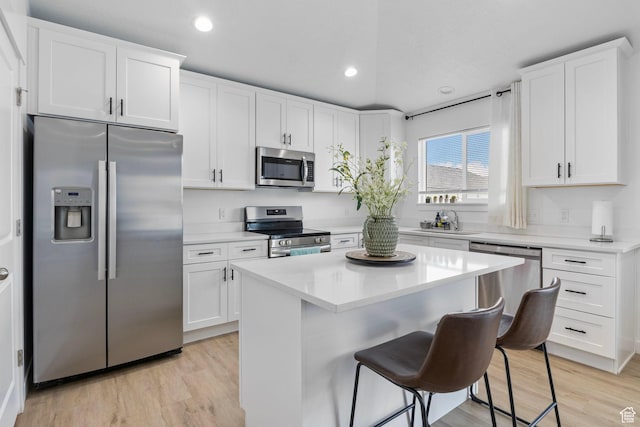 2256 E Boxwood Ln, Eagle Mountain, UT 84005 - kitchen with stainless steel appliances, a sink, a breakfast bar area, white cabinets, and light countertops