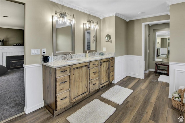 875 E Burch Creek Holw S, South Ogden, UT 84403 - full bathroom featuring a fireplace, wood finished floors, ornamental molding, wainscoting, and double vanity
