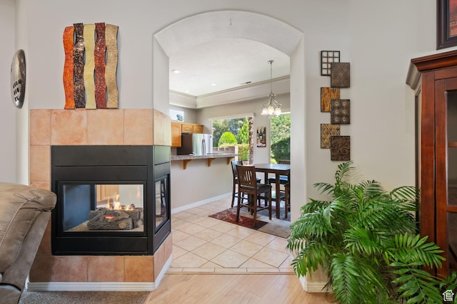 corridor featuring baseboards, arched walkways, light wood-type flooring, a chandelier, and recessed lighting