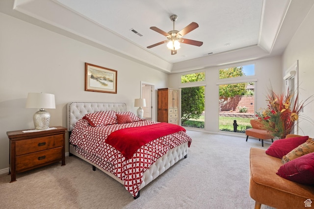 carpeted bedroom featuring a raised ceiling and ceiling fan