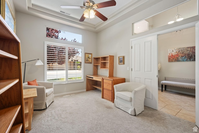 sitting room with ceiling fan, a desk, a towering ceiling, a tray ceiling, and light colored carpet