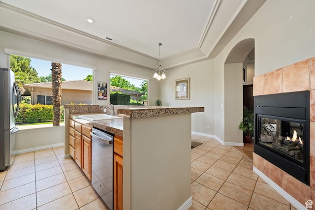 kitchen with stainless steel appliances, light tile patterned floors, a tile fireplace, a sink, and arched walkways