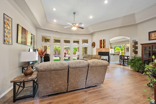 living room with arched walkways, ceiling fan, a raised ceiling, recessed lighting, and light wood finished floors