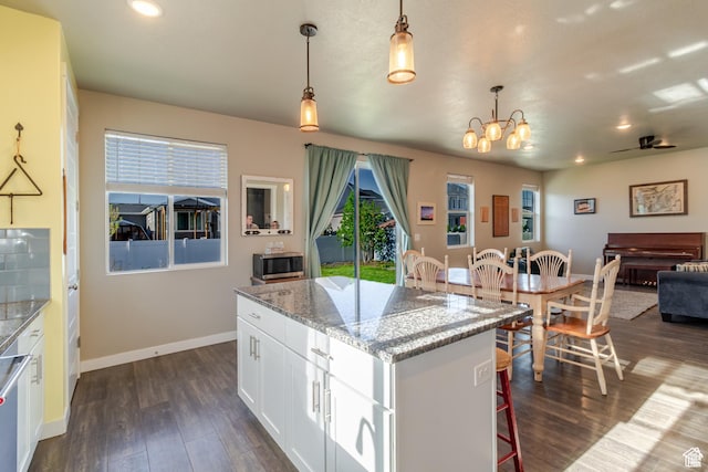 1517 E Kelsey Dr, Eagle Mountain, UT 84005 - kitchen with stainless steel microwave, a center island, dark wood-style flooring, a chandelier, and white cabinets