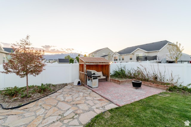 1517 E Kelsey Dr, Eagle Mountain, UT 84005 - patio terrace at dusk with a fenced backyard, a shed, and an outbuilding