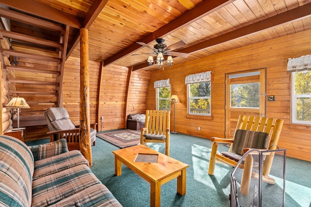 carpeted living room featuring beamed ceiling, wood walls, wooden ceiling, and ceiling fan