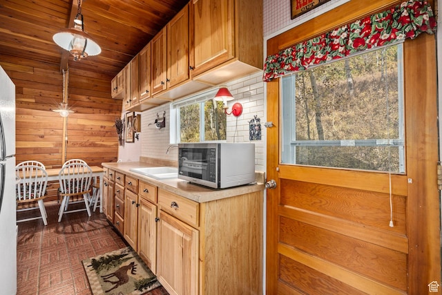kitchen with stainless steel microwave, a sink, wood walls, light countertops, and wooden ceiling