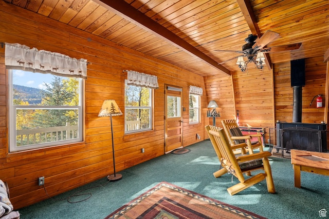 living area with carpet floors, wooden ceiling, wood walls, beamed ceiling, and a ceiling fan