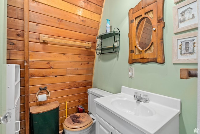 bathroom with wood walls, toilet, and vanity