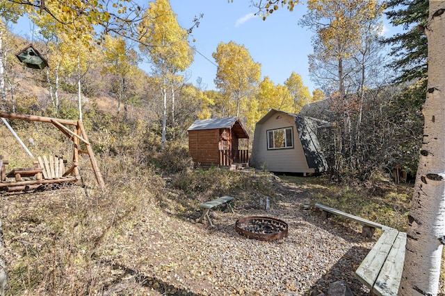 view of yard featuring an outdoor fire pit, a storage unit, and an outdoor structure