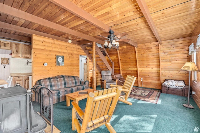 carpeted living area with beamed ceiling, ceiling fan, wooden walls, wooden ceiling, and stairs