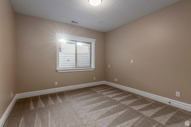 carpeted spare room with baseboards and a textured ceiling