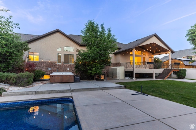 rear view of property with a hot tub, a patio area, stairs, and a wooden deck