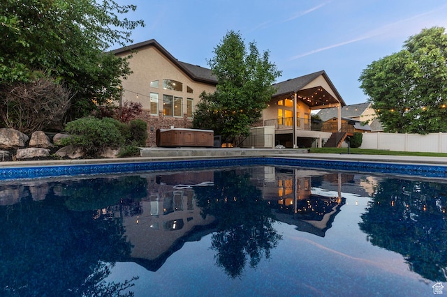 view of swimming pool with fence, a hot tub, and stairs
