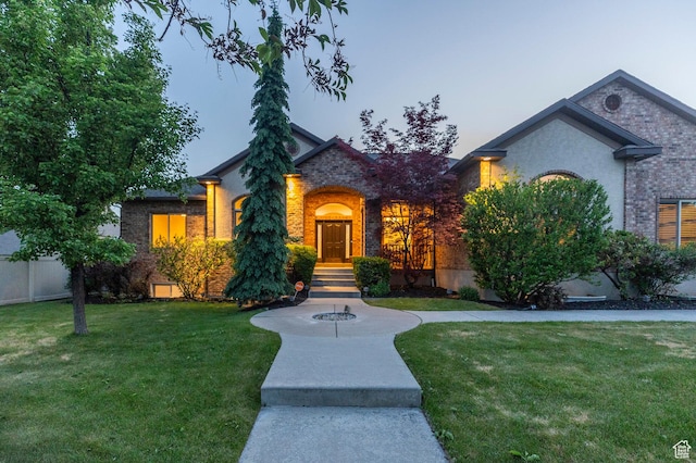 view of front of house with a lawn and brick siding