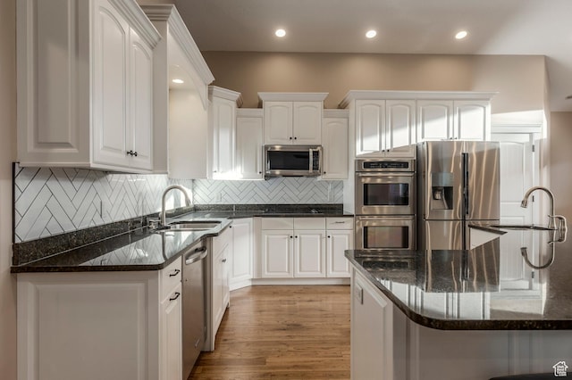 kitchen featuring appliances with stainless steel finishes, a sink, white cabinetry, and recessed lighting