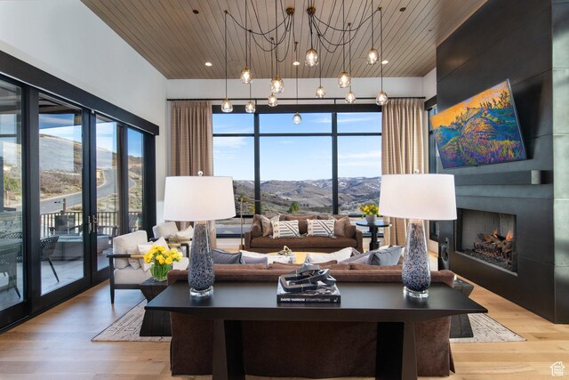 living room featuring wooden ceiling, a warm lit fireplace, healthy amount of natural light, and light wood-style floors