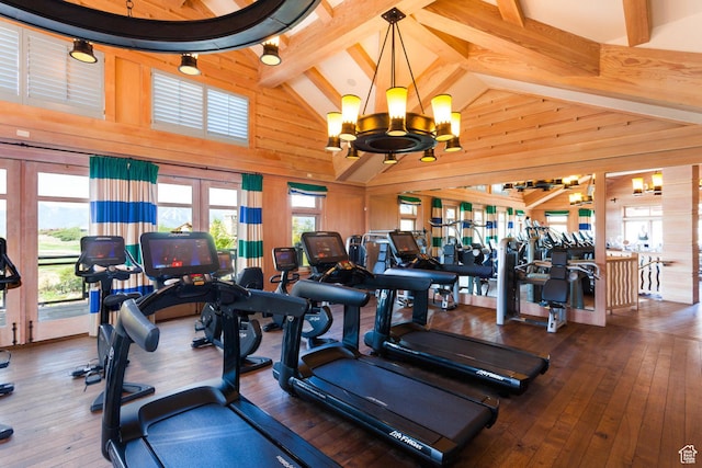 gym featuring wood walls, hardwood / wood-style floors, beamed ceiling, a chandelier, and high vaulted ceiling