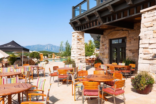 view of patio with a mountain view, a community pool, and outdoor dining space