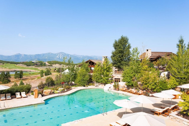view of pool with a mountain view, a patio, and a water slide