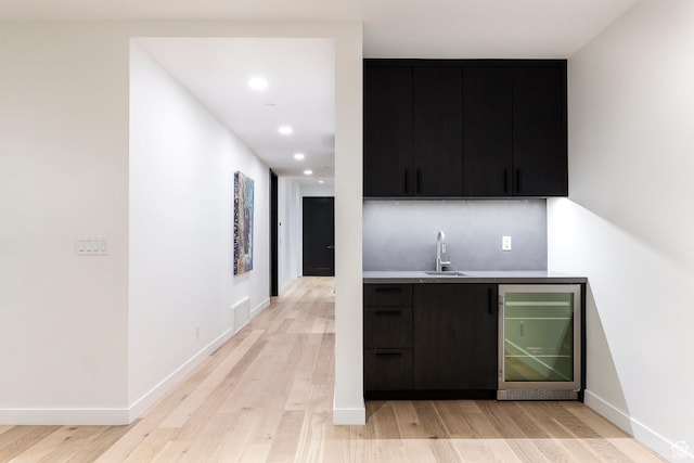 indoor wet bar featuring beverage cooler, light wood-style floors, recessed lighting, and baseboards