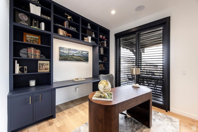 home office with light wood finished floors, baseboards, and built in shelves