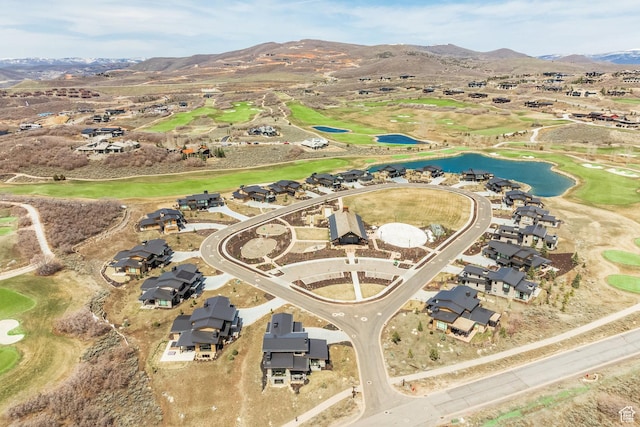 view of property location with a water and mountain view, a golf club, and nearby suburban area