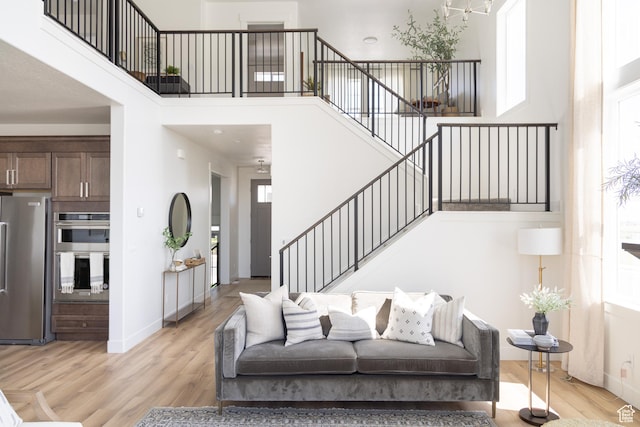 6489 W Yawkey Way, Herriman, UT 84096 - living area with stairs, light wood finished floors, a high ceiling, baseboards, and a chandelier
