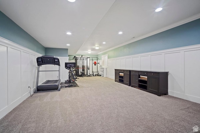 workout area featuring a decorative wall, carpet flooring, recessed lighting, ornamental molding, and a wainscoted wall
