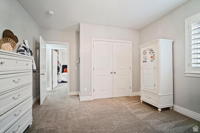 carpeted bedroom featuring a closet and baseboards