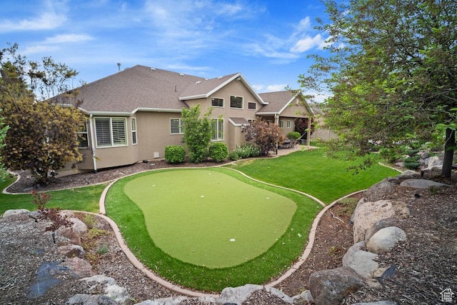 surrounding community with an area to practice putting, a patio area, and a yard